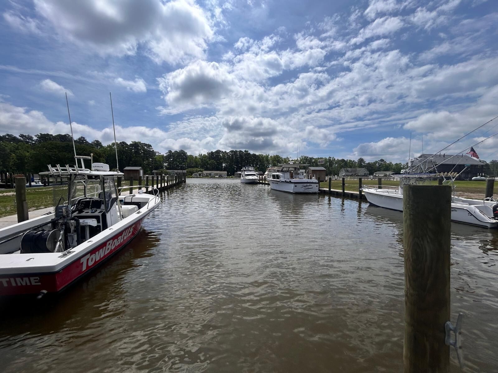 A marina with boats docked, a clear sky, and a calm water surface.
