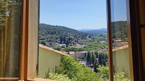 Une fenêtre donnant sur un paysage rural, avec des maisons et des arbres.