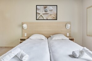 Habitación de hotel con cama doble, dos mesitas de noche, un cuadro concaracoles y cabecero de madera.