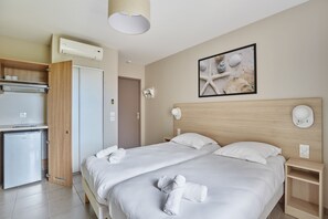 Una habitación de hotel con una cama, una kitchenette pequeña y un aire acondicionado instalado en la pared.
