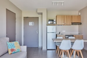 Una cocina moderna con armarios de madera, un refrigerador, un microondas y una mesa de comedor con sillas.