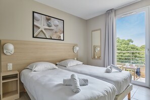 Habitación de hotel con dos camas, una obra de arte con forma de estrella de mar, un ventanal con vistas y un balcón.