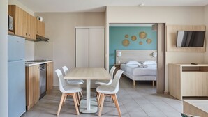 A modern kitchen with a dining area, a bed, and a TV. - Residence Odalys Les Oceanides (La Londe-les-Maures)