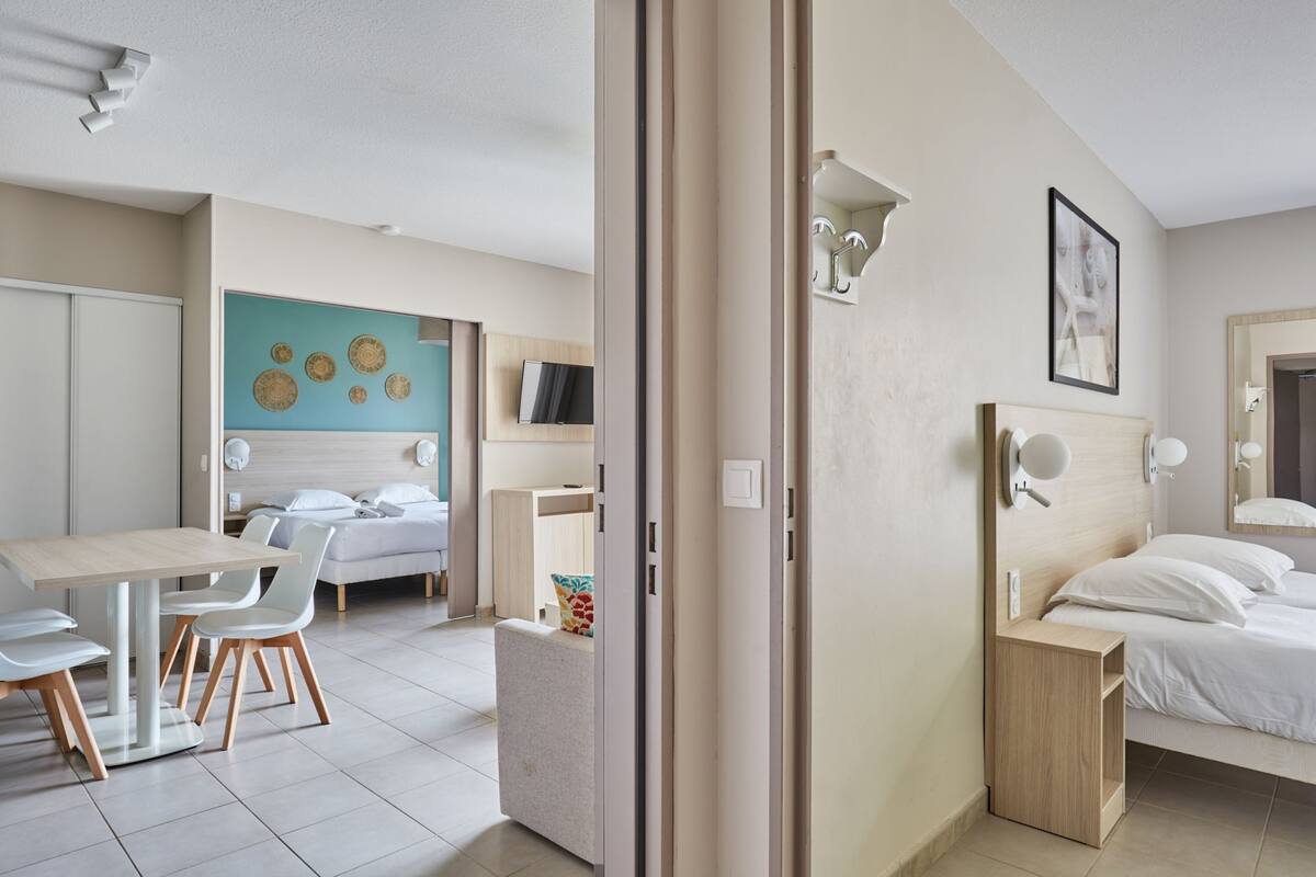 A modern hotel room with a bed, bedside table, and a desk with chairs.