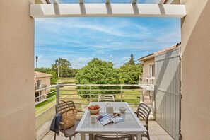 A balcony with a table set for breakfast, including croissants, a newspaper, and a coffee cup.