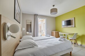 Una habitación de hotel con dos camas, televisión, escritorio y silla.
