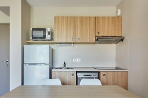 Una cocina compacta con armarios de madera, microondas integrado, refrigerador y lavavajillas.