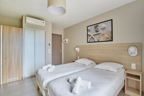 Habitación de hotel con cama doble, cabecera de madera, obra de arte colgada en la pared y mesita de noche con lámpara.