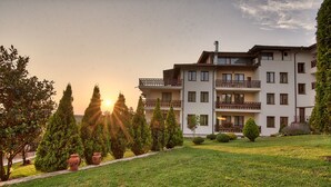 A multi-story hotel with balconies, a well-maintained lawn, and a sunset view. - Park hotel Arbanasi (Veliko Tarnovo)