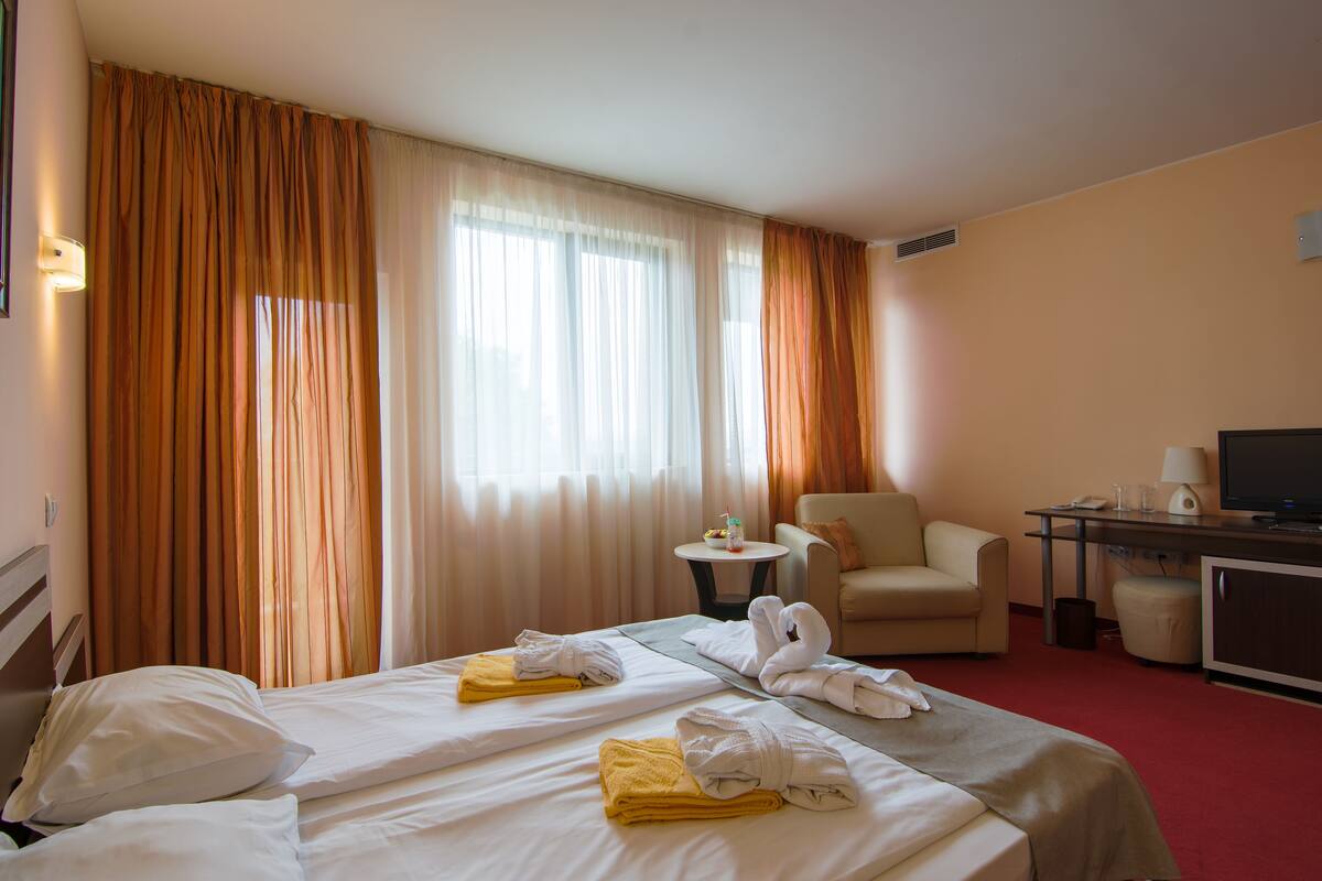 Una habitación de hotel con dos camas, un escritorio, una silla y un televisor.