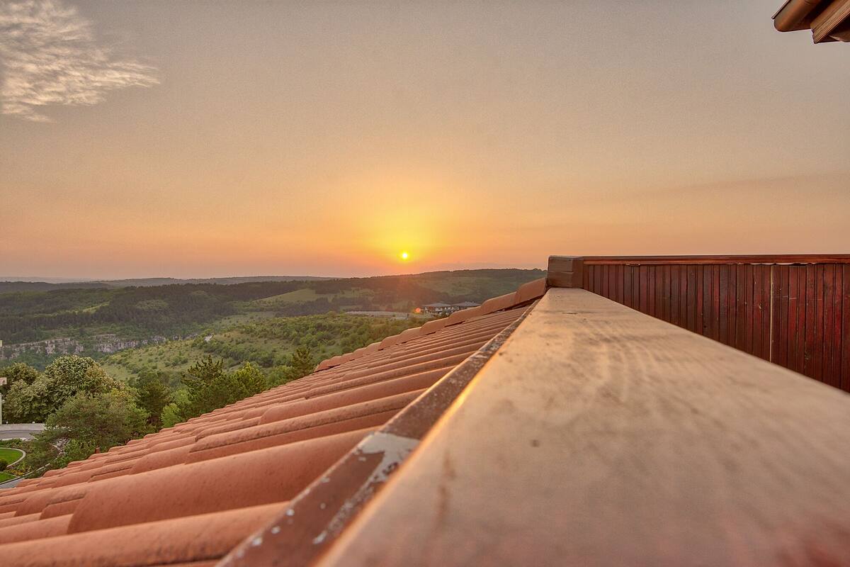 Un balcón de madera con vistas a un paisaje pintoresco al atardecer.