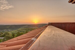 Un balcón de madera con vistas a un paisaje pintoresco al atardecer.