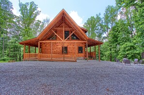A wooden cabin with a porch, surrounded by trees. - Whispering Trees Lodge (South Bloomingville)