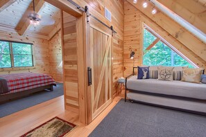 Une chambre mansardée chaleureuse, avec un lit, un canapé et une grande fenêtre.