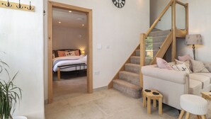 A modern interior with a staircase, a bed, a sofa, and a wall clock. - Meadow Syke Barn (Penrith)