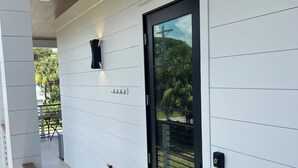 A modern exterior with a wooden ceiling, a black door, and a small wooden bench. - Suite A - 3 minutes walk to Center of Folly Beach, across from beach-1 Room (Folly Beach)