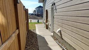 Un sentier bordé d’une clôture en bois et de petits cailloux, qui mène à un bâtiment à l’extérieur gris.