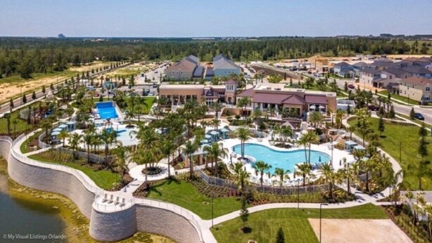A resort with multiple buildings, a large central pool, and a surrounding landscaped area. - Beautiful 5 Bedroom Town Home with Splash Pool (Kissimmee)