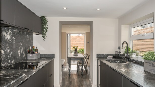 A modern kitchen with dark cabinetry, a marble countertop, and a central island. - 15 Rosemary Lane (Beaumaris)