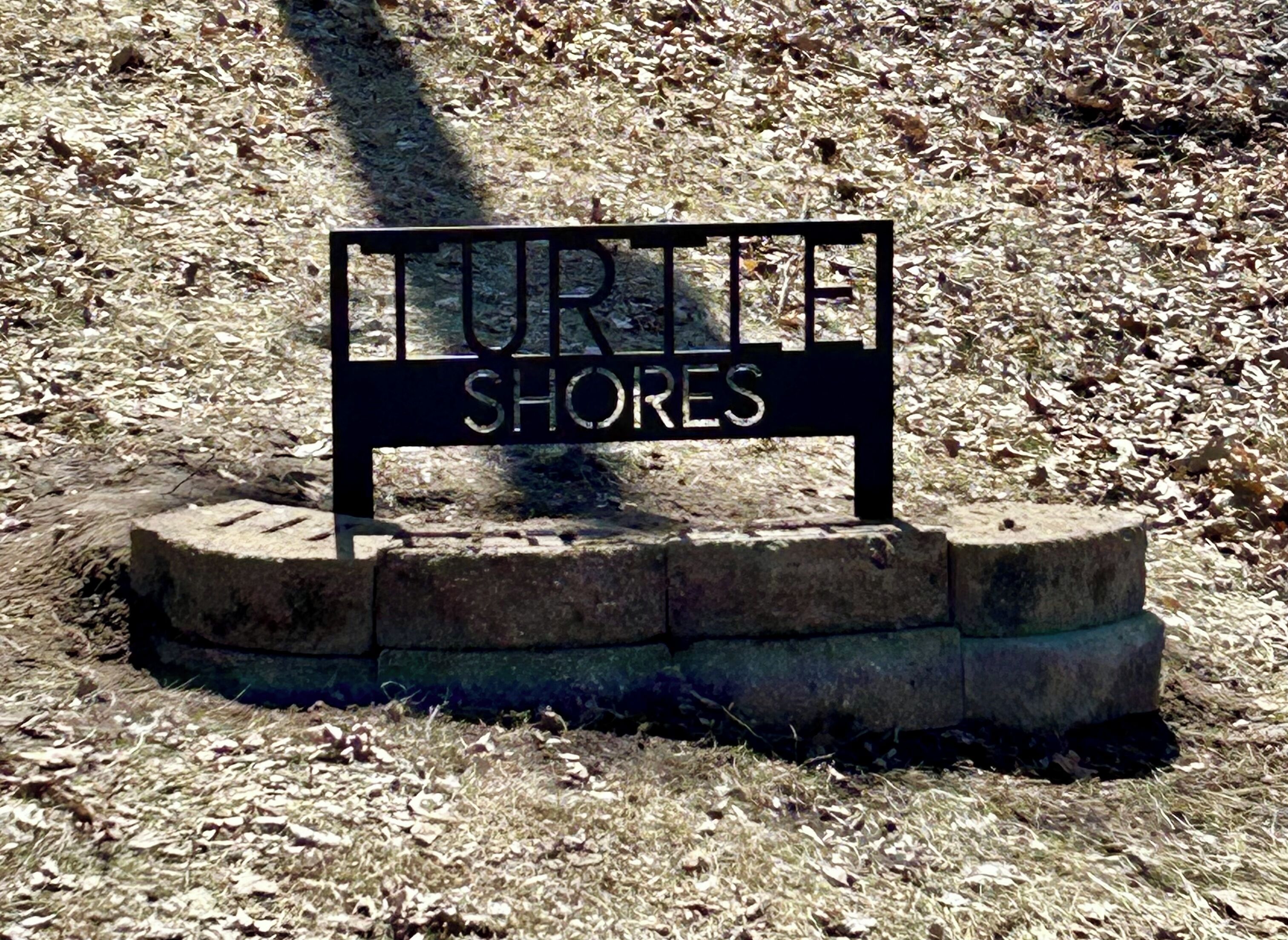 A sign reading "Turtle Shores" on a stone base.