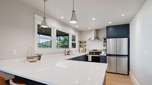 A modern kitchen with a large island, stainless steel appliances, and pendant lighting. - Silverado Beach Lake House (Clearlake)