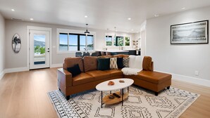 A modern living room with a brown sectional sofa, a white coffee table, and a patterned rug. - Silverado Beach Lake House (Clearlake)