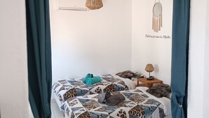 Une chambre à coucher comprenant un lit, une table de chevet, une lampe suspendue et un élément décoratif mural.