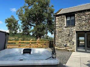 Ein Steinhaus mit Whirlpool und Holzzaun.