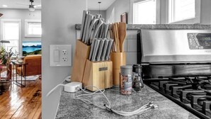 Una cocina con estufa de acero inoxidable, un bloque de cuchillos y una cafetera sobre la encimera.