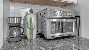 Una cocina con cafetera, una taza con forma de cactus y horno empotrado.
