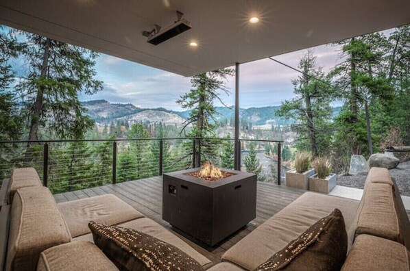 Relax in the outdoor seating area with a fire pit, sofas, and a projector.