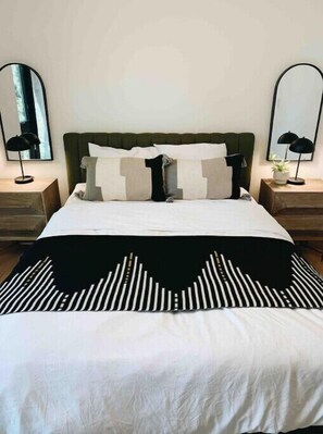 Cozy retreat with a large bed, dark green headboard, and two bedside lamps.