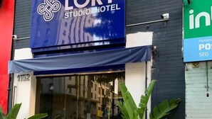 Entrada de hotel com toldo azul exibindo o nome 'LORY STUDIO HOTEL'.