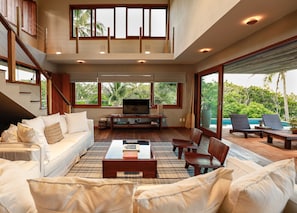 A spacious living room with a large TV, comfortable seating, and a view of lush greenery. - Casa Beira Mar - Praia de São José e Prainha (Itacaré)