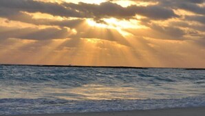 Ein Strand mit Wellen und einem Sonnenuntergang.