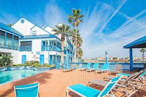 A resort with a pool, lounge chairs, and palm trees. - Spinnaker 217 Waterfront 2/2 Condo/Pool/ Boat Slip/Hot Tub (Corpus Christi)