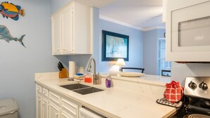 A kitchen with white cabinets, a stove, a sink, and a dishwasher.