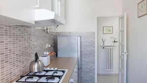 A compact kitchen with a gas stove, a kettle, and a refrigerator. - Cleo Giglio  (Ancona)