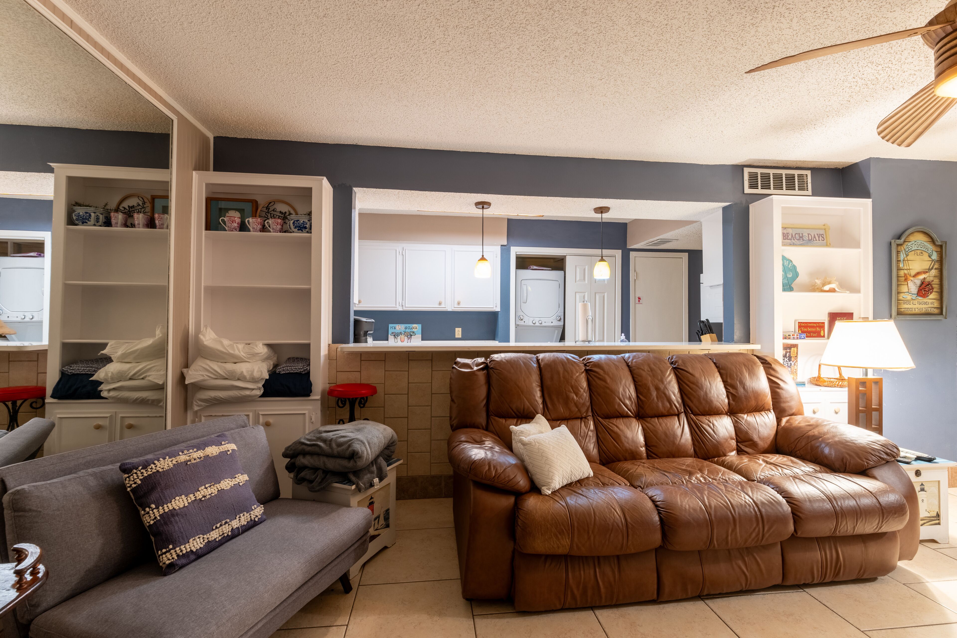 A living room with a brown leather sofa, a grey sofa, and a white cabinet with decorative items.