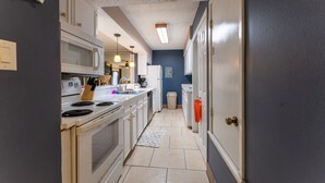 A kitchen with white cabinets, a microwave, stove, and a trash can. - Waterfront Condo: Stunning Sunsets, Fishing, Patio, & 4 minutes from the beach!  (Corpus Christi)