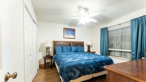 A bedroom with a bed, a ceiling fan, a window with curtains, and a door. - Waterfront Condo: Stunning Sunsets, Fishing, Patio, & 4 minutes from the beach!  (Corpus Christi)