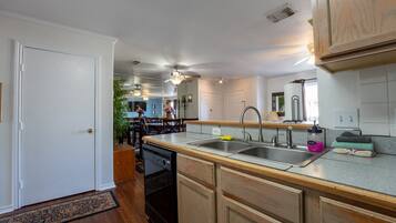 A kitchen with wooden cabinets, a built-in dishwasher, and a large island with a sink.