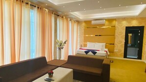 A hotel room with a bed, two sofas, a small table, and a window with curtains. - Mikayla Resort (Chilaw)