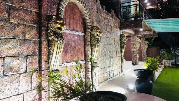 A stone wall with lion sculptures and a potted plant. - Mikayla Resort (Chilaw)