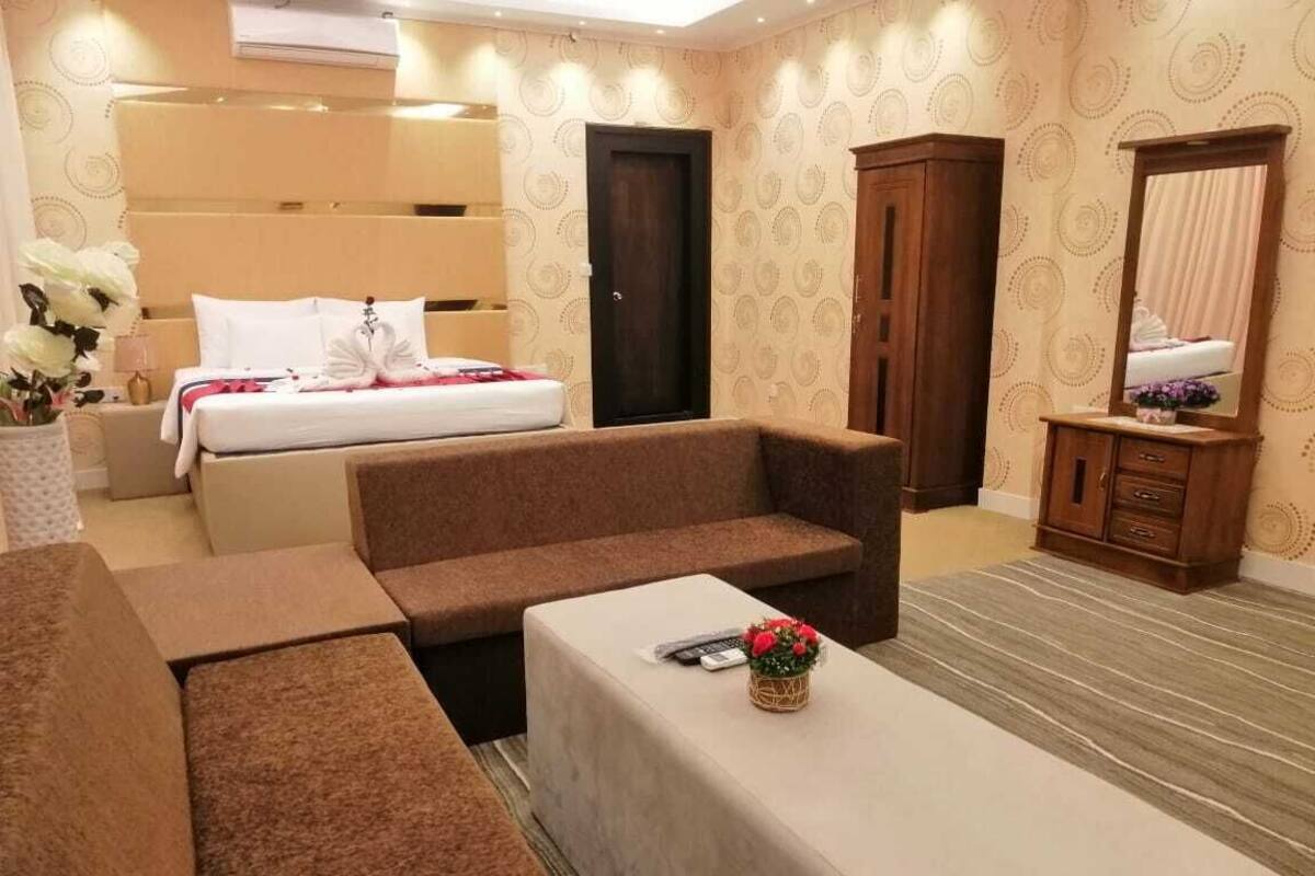 Ein Hotelzimmer mit Bett, Sofa, kleinem Tisch, Schrank und Spiegel.
