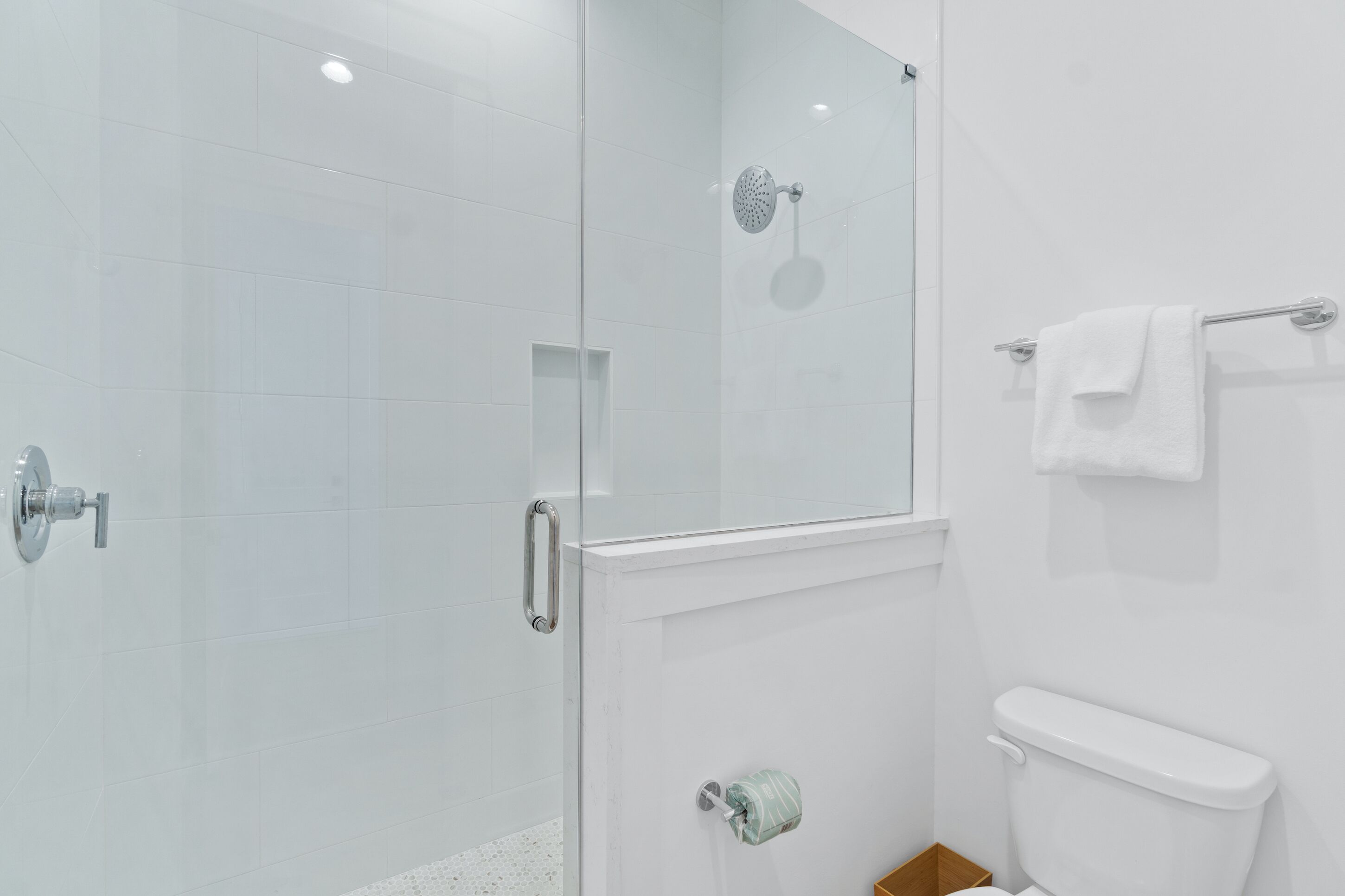 Un baño moderno con cabina de ducha de vidrio, inodoro y perchero para toallas.