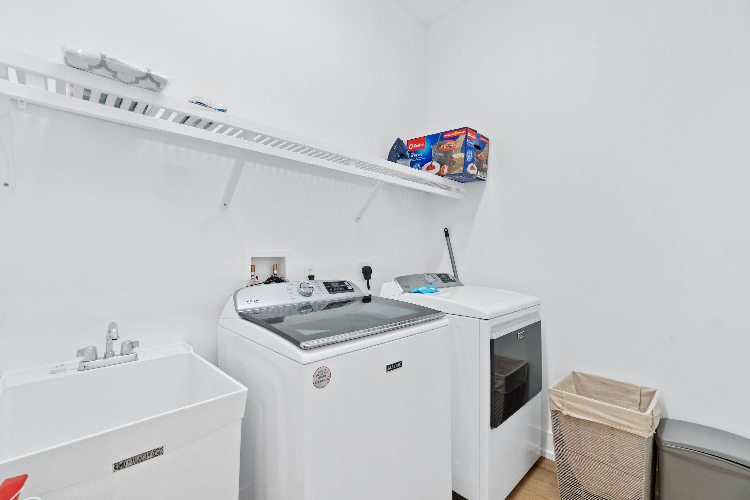 A laundry room with a washing machine, dryer, and a shelf with detergent boxes.