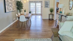 Una sala de estar moderna con comedor, piso de madera y decoración contemporánea.