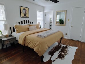 Une chambre à coucher avec un lit, une table de chevet, une lampe, un miroir et un tapis en peau de vache.