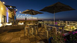 An outdoor terrace with wooden flooring, bar area, and umbrellas. - Luxury 1BR Condo in Silicon Valley's Heart (Menlo Park)